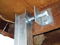 Securing the i-beam system to the top of the floor joist in a foundation wall repair in Plymouth.